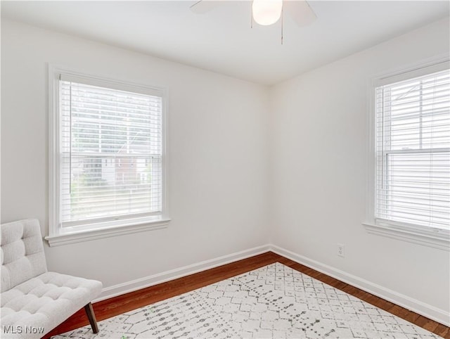 sitting room with ceiling fan, baseboards, and wood finished floors