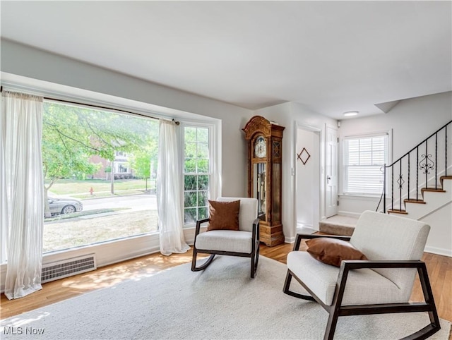 living area with visible vents, stairway, baseboards, and wood finished floors