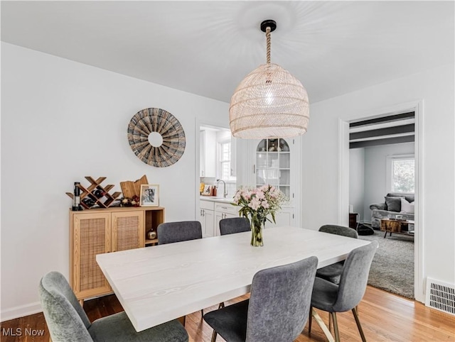 dining space featuring light wood-style flooring, visible vents, and baseboards