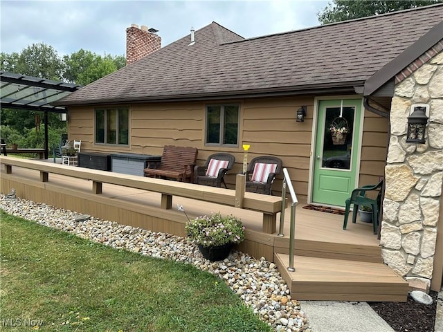 back of property with a lawn, a jacuzzi, a deck, and a pergola