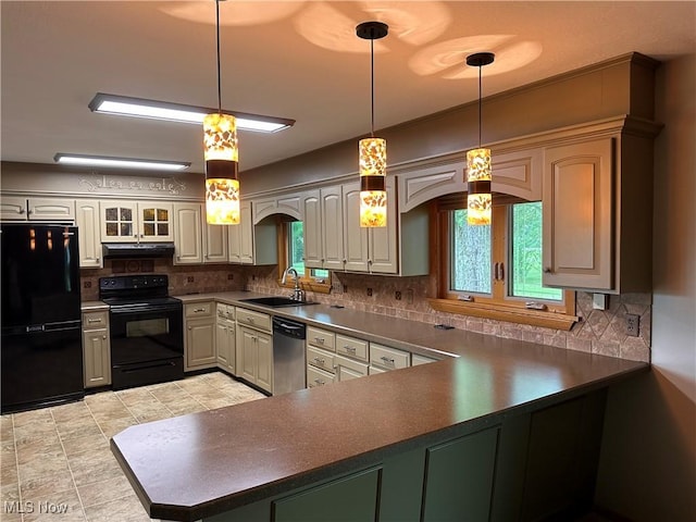 kitchen with dark countertops, backsplash, under cabinet range hood, black appliances, and a sink