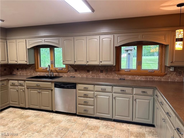 kitchen with dark countertops, tasteful backsplash, pendant lighting, dishwasher, and a sink