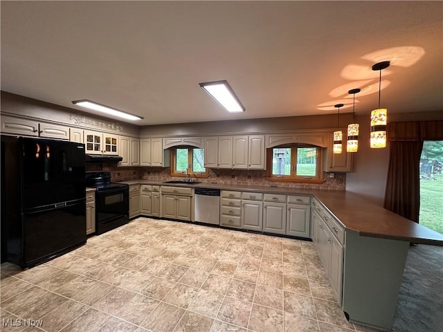 kitchen with a peninsula, a sink, decorative backsplash, black appliances, and dark countertops