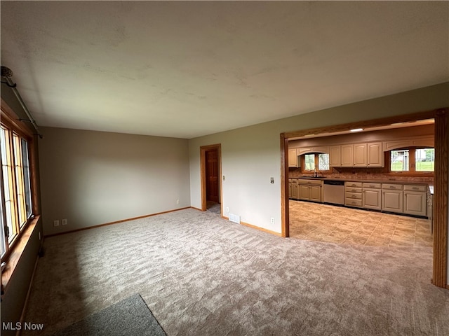 unfurnished living room featuring light carpet and sink