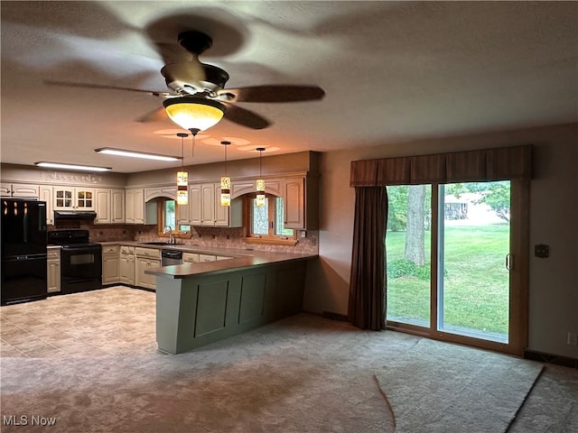 kitchen featuring range with electric stovetop, a healthy amount of sunlight, black fridge, and kitchen peninsula