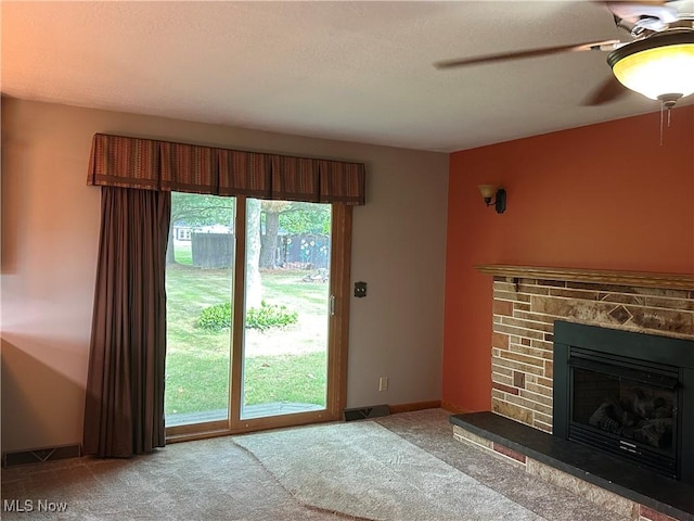 unfurnished living room featuring visible vents, baseboards, ceiling fan, a stone fireplace, and carpet flooring