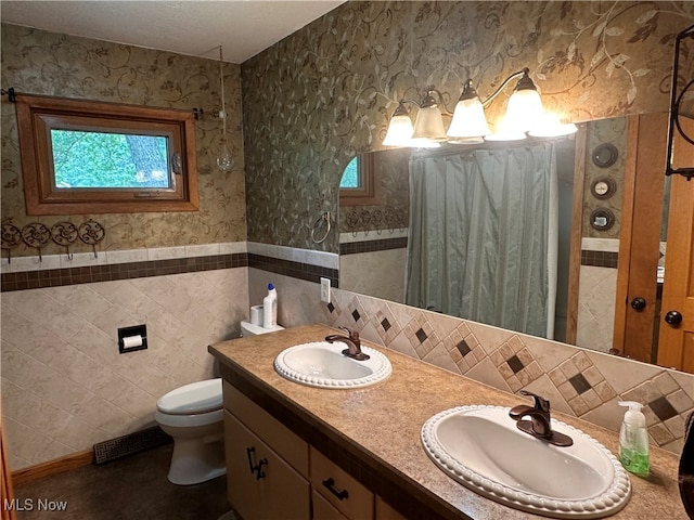 bathroom featuring tile walls, dual bowl vanity, toilet, and backsplash