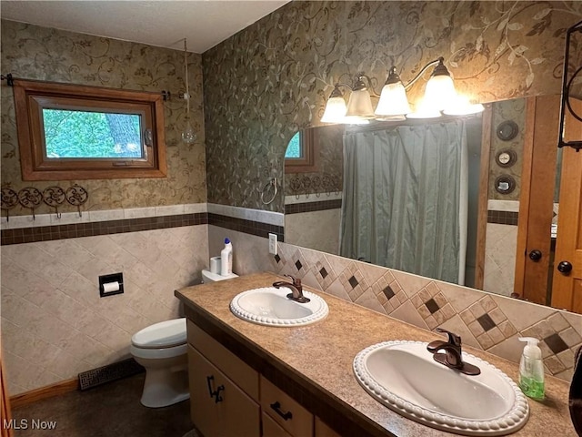 bathroom featuring visible vents, wallpapered walls, a sink, tile walls, and toilet