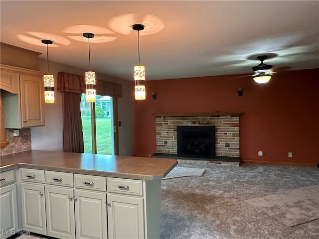 kitchen with a stone fireplace, kitchen peninsula, hanging light fixtures, decorative backsplash, and ceiling fan