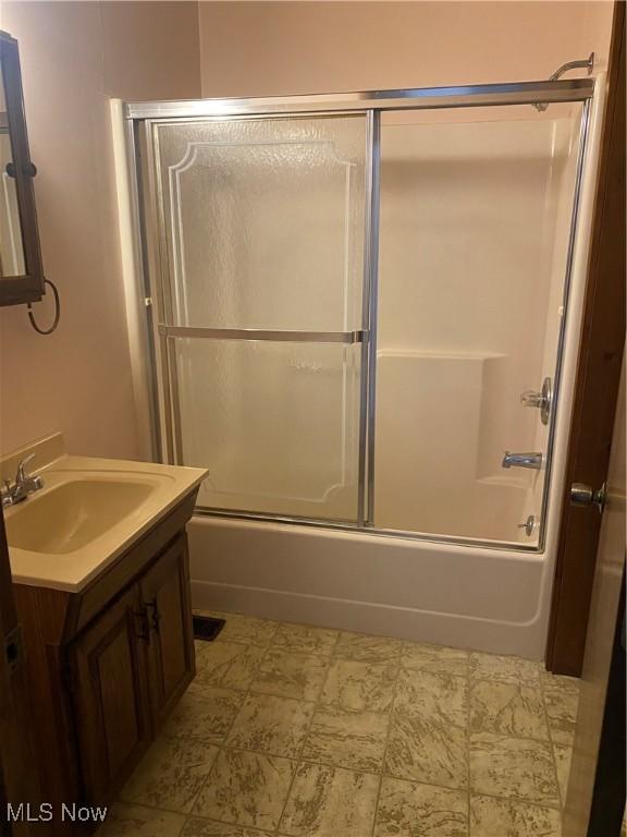 bathroom with combined bath / shower with glass door and vanity