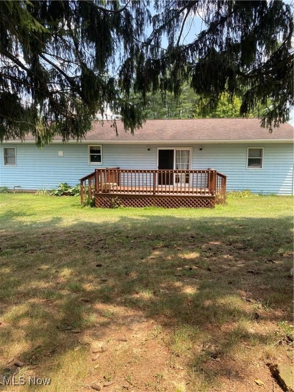 back of house featuring a wooden deck and a yard