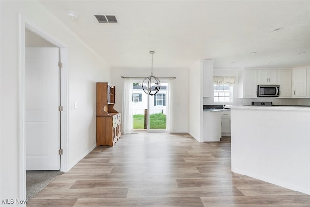 kitchen featuring an inviting chandelier, white cabinetry, light hardwood / wood-style flooring, and decorative light fixtures