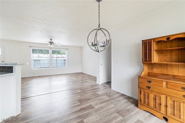 unfurnished dining area featuring a textured ceiling, ceiling fan with notable chandelier, and light hardwood / wood-style floors