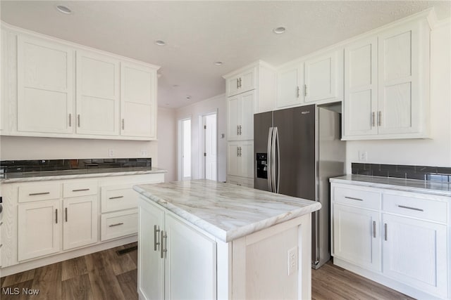 kitchen with white cabinets, a center island, light stone counters, wood-type flooring, and stainless steel refrigerator with ice dispenser