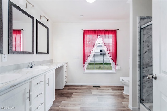 bathroom with toilet, a healthy amount of sunlight, hardwood / wood-style flooring, and double vanity