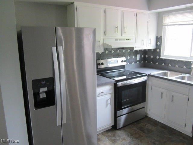 kitchen featuring white cabinetry, wall chimney exhaust hood, sink, appliances with stainless steel finishes, and backsplash