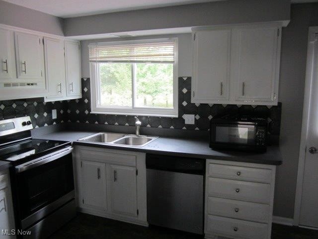 kitchen with appliances with stainless steel finishes, tasteful backsplash, sink, white cabinetry, and range hood