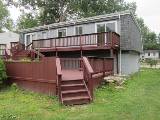 back of property with a wooden deck and a lawn