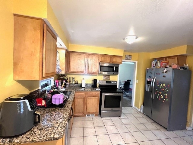 kitchen featuring dark stone counters, stainless steel appliances, and light tile patterned floors