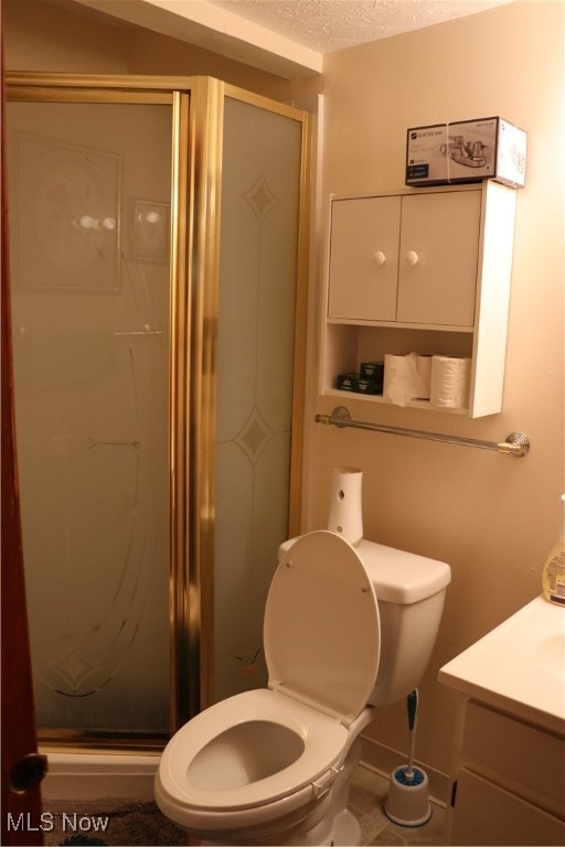 bathroom featuring vanity, toilet, a textured ceiling, and walk in shower