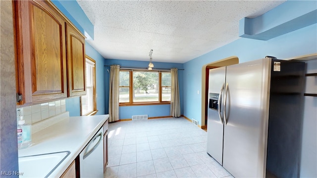 kitchen featuring a textured ceiling, sink, decorative light fixtures, white dishwasher, and stainless steel fridge