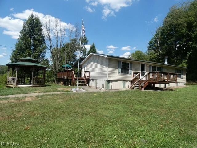 rear view of property featuring a gazebo, a yard, and a deck