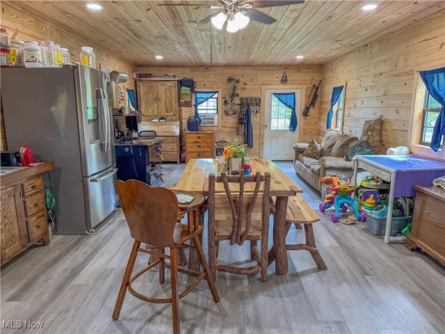 dining room featuring ceiling fan, wooden ceiling, light wood-type flooring, and wood walls