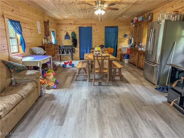 dining area with wood walls, wooden ceiling, and light hardwood / wood-style flooring