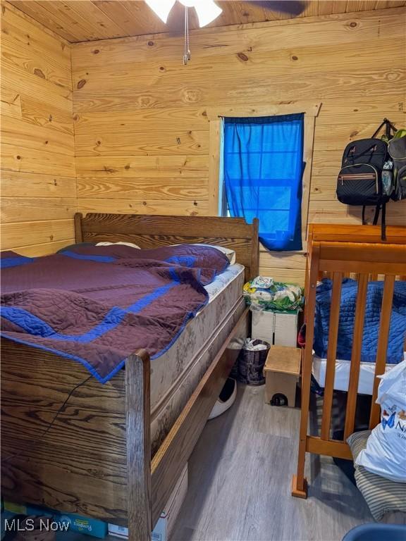 bedroom with wood-type flooring, wood ceiling, and wood walls