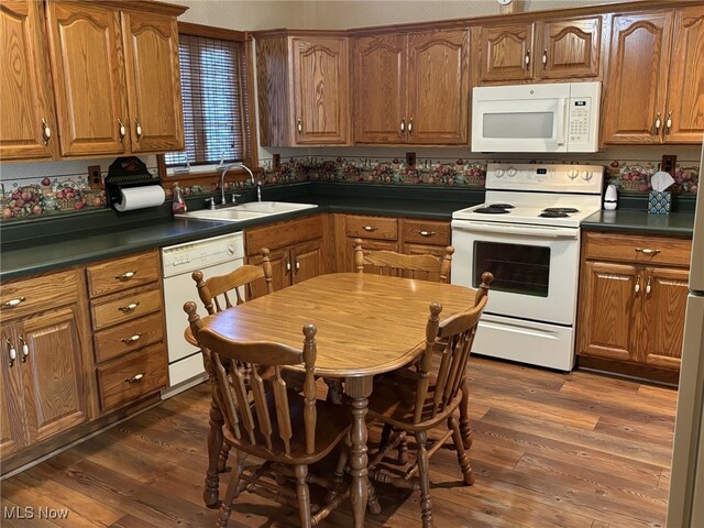 kitchen with dark hardwood / wood-style flooring, white appliances, and sink