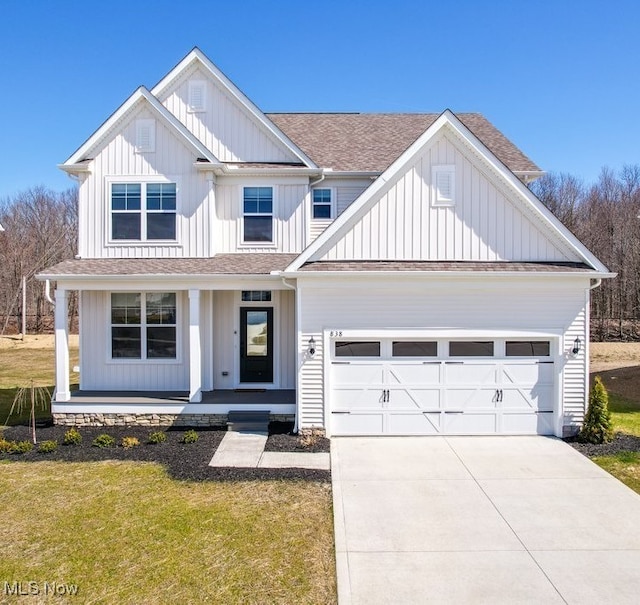 view of front of home featuring covered porch, a garage, and a front lawn