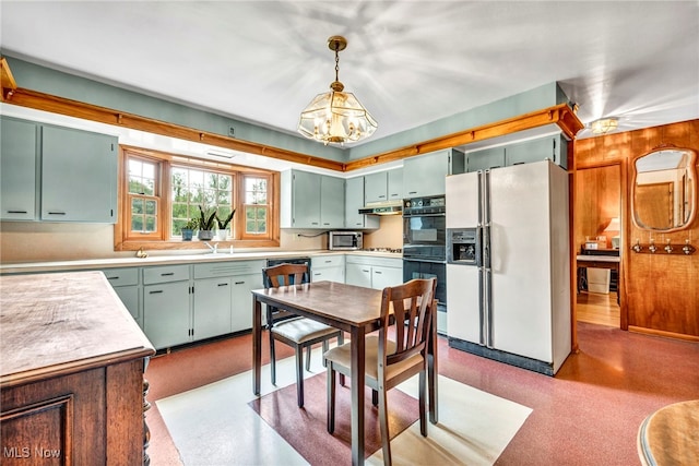 kitchen with a notable chandelier, black appliances, hanging light fixtures, sink, and light hardwood / wood-style flooring