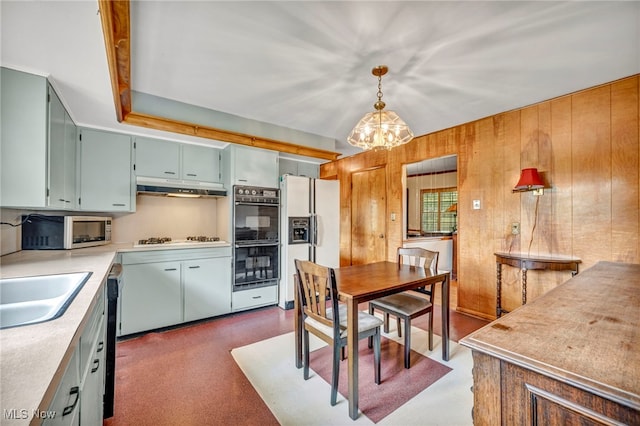 kitchen with decorative light fixtures, dark carpet, white appliances, and a chandelier