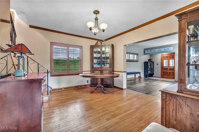 home office with crown molding, baseboard heating, a notable chandelier, and hardwood / wood-style floors