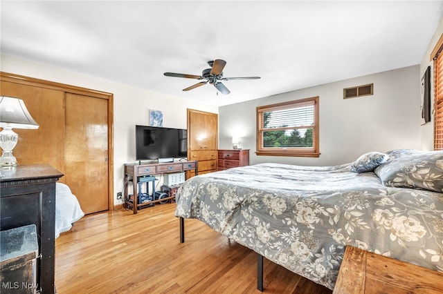 bedroom featuring two closets, ceiling fan, and light hardwood / wood-style flooring