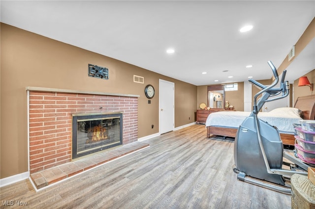 bedroom with hardwood / wood-style flooring and a brick fireplace