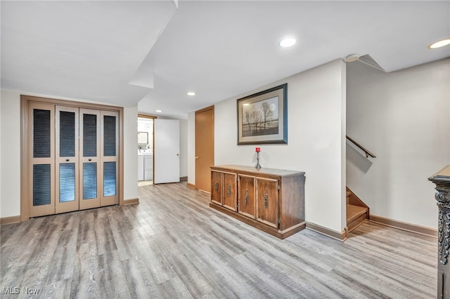 unfurnished living room featuring washing machine and clothes dryer and light hardwood / wood-style floors