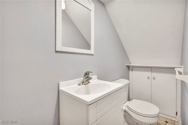 bathroom with vanity, tile patterned floors, toilet, and vaulted ceiling