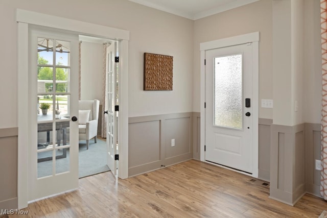 foyer entrance featuring light hardwood / wood-style floors, crown molding, and french doors