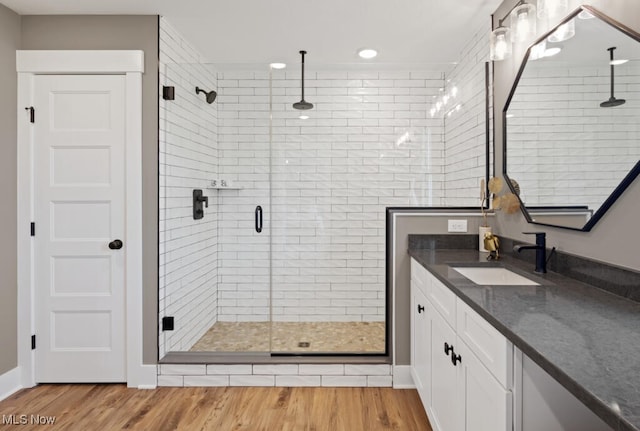 bathroom with hardwood / wood-style flooring, a shower with door, and vanity