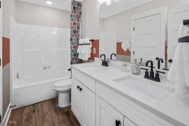 full bathroom featuring toilet, hardwood / wood-style floors, double sink vanity, and shower / tub combination