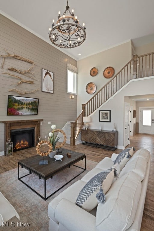 living room with a high ceiling, crown molding, a chandelier, and wood-type flooring