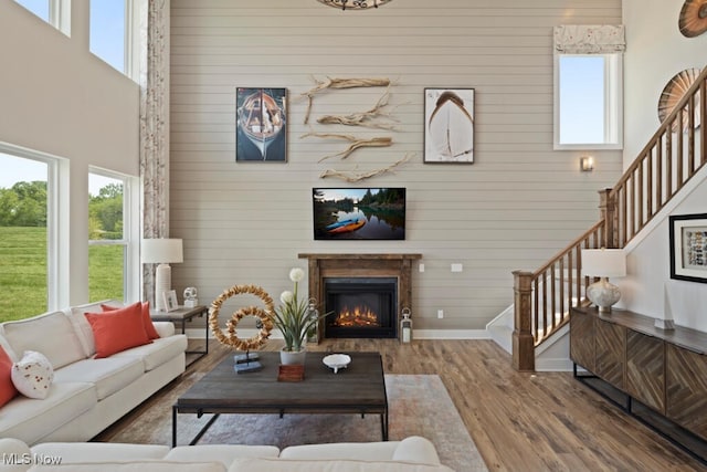 living room with hardwood / wood-style floors, a towering ceiling, and wooden walls