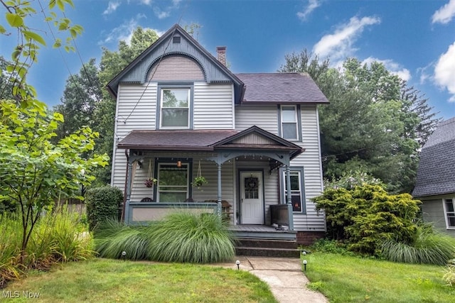 victorian house featuring a porch and a front lawn