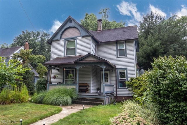 victorian house featuring a porch and a front yard