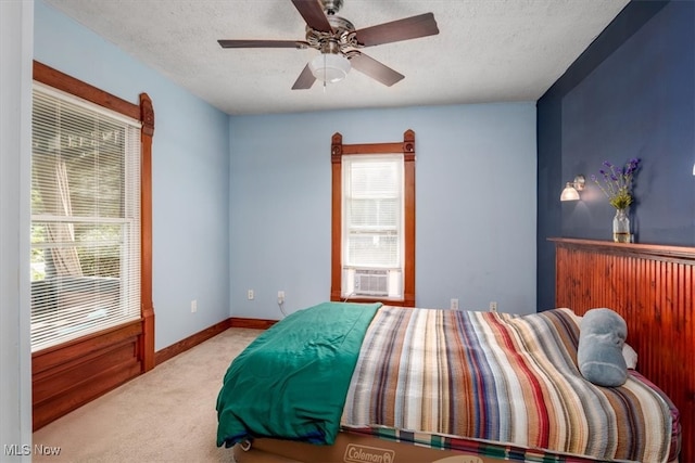 bedroom with light colored carpet, a textured ceiling, ceiling fan, and cooling unit