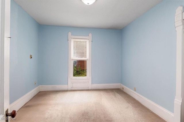 empty room featuring baseboards and light colored carpet