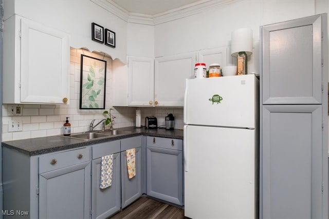 kitchen with white refrigerator, crown molding, sink, backsplash, and dark wood-type flooring