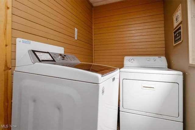 washroom with laundry area, washing machine and dryer, and wood walls