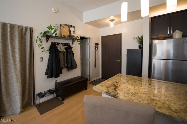 kitchen featuring light stone counters, freestanding refrigerator, decorative light fixtures, and light wood-style floors